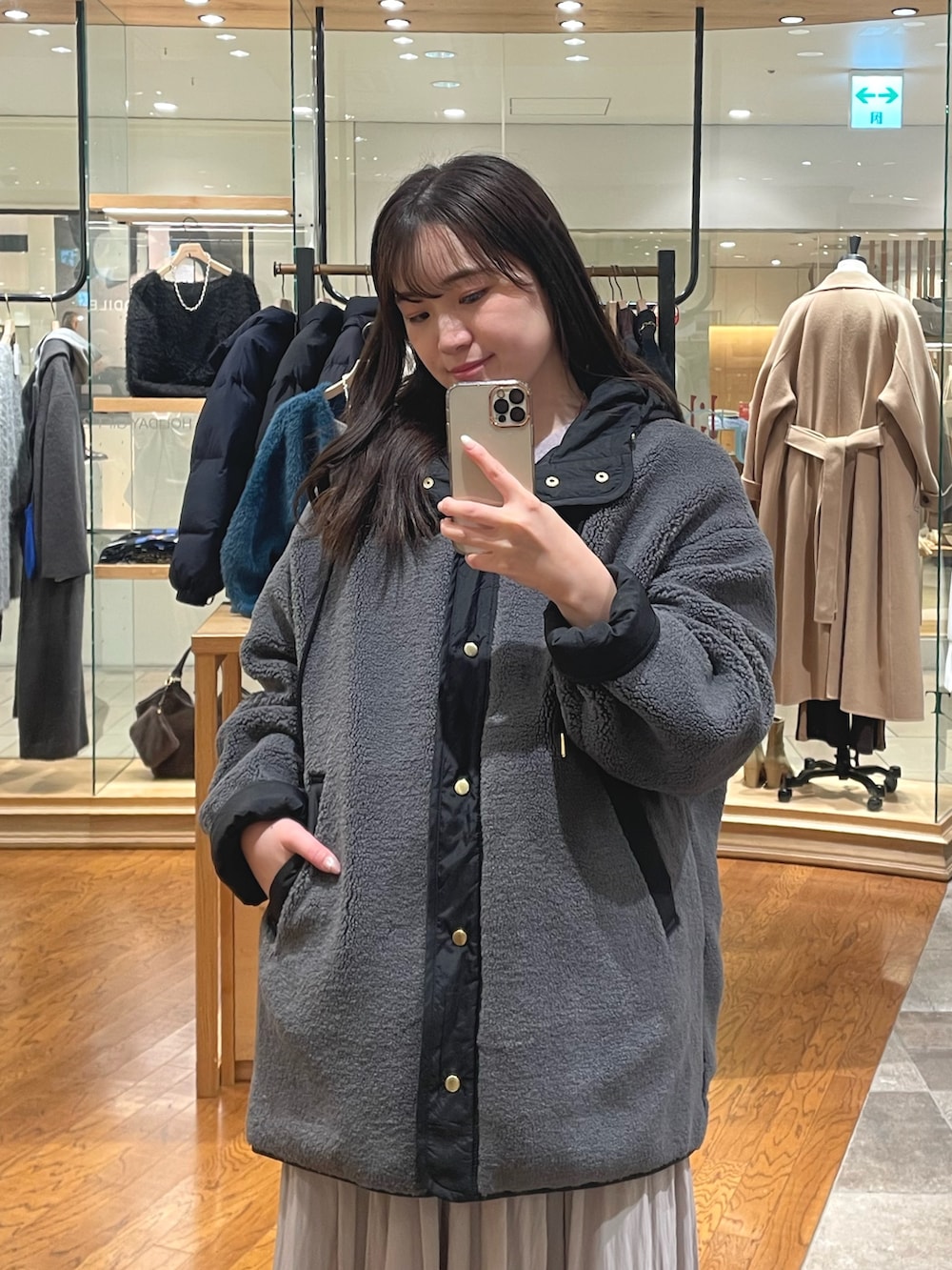 グレー系のその他アウター、ベージュ系のスカート、ブラウン系のブーツを着用したレディースの冬コーディネートの2枚目の写真