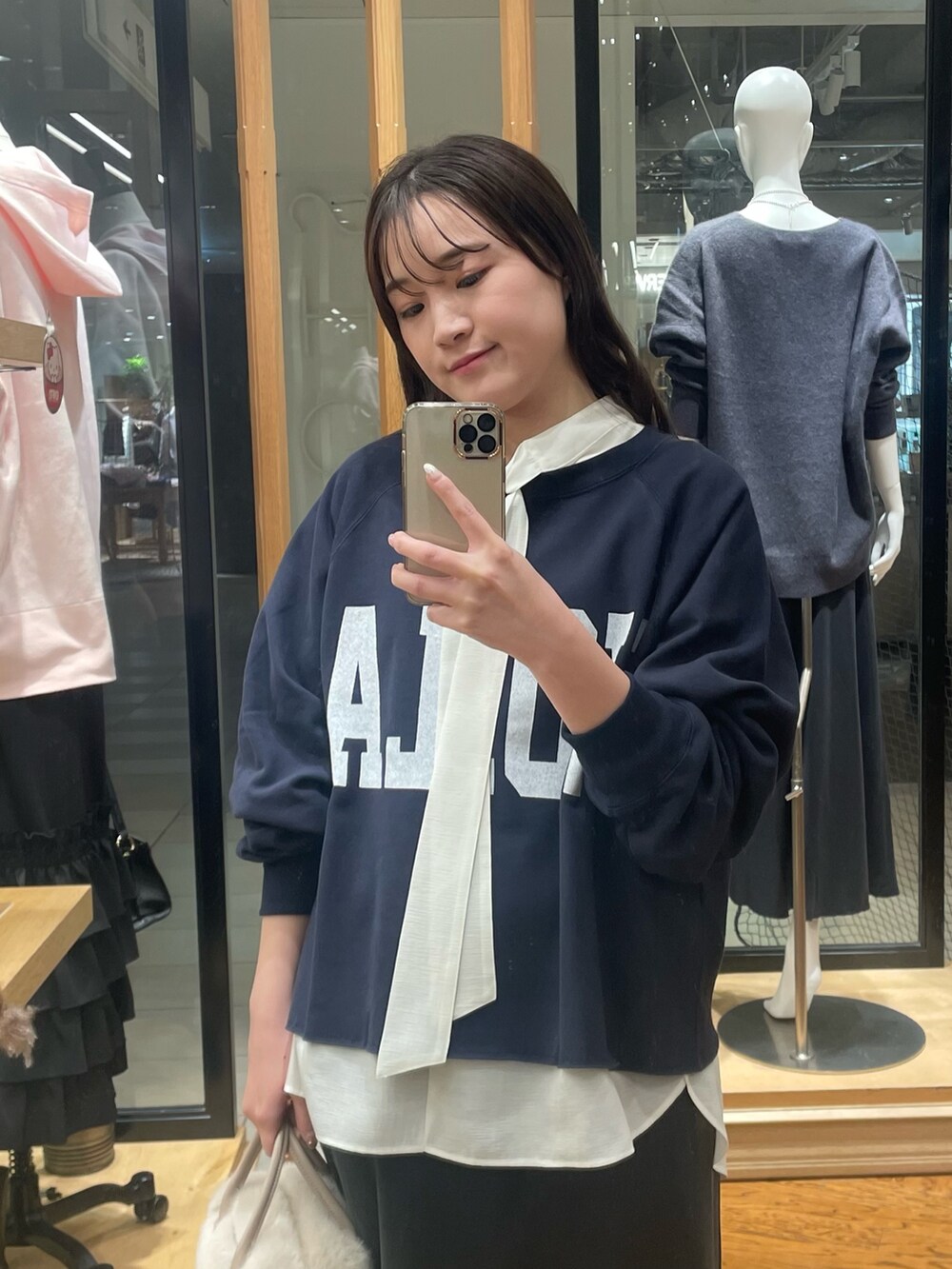 ブラック系のスカート、ベージュ系のボストンバッグ、ブルー系のスウェットを着用したレディースの冬コーディネートの2枚目の写真