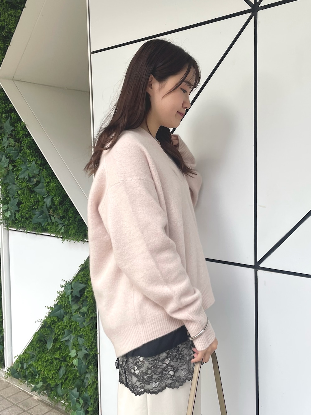 ベージュ系のハンドバッグ、ブラック系のパンプス、ピンク系のニット/セーターを着用したレディースの秋コーディネートの3枚目の写真