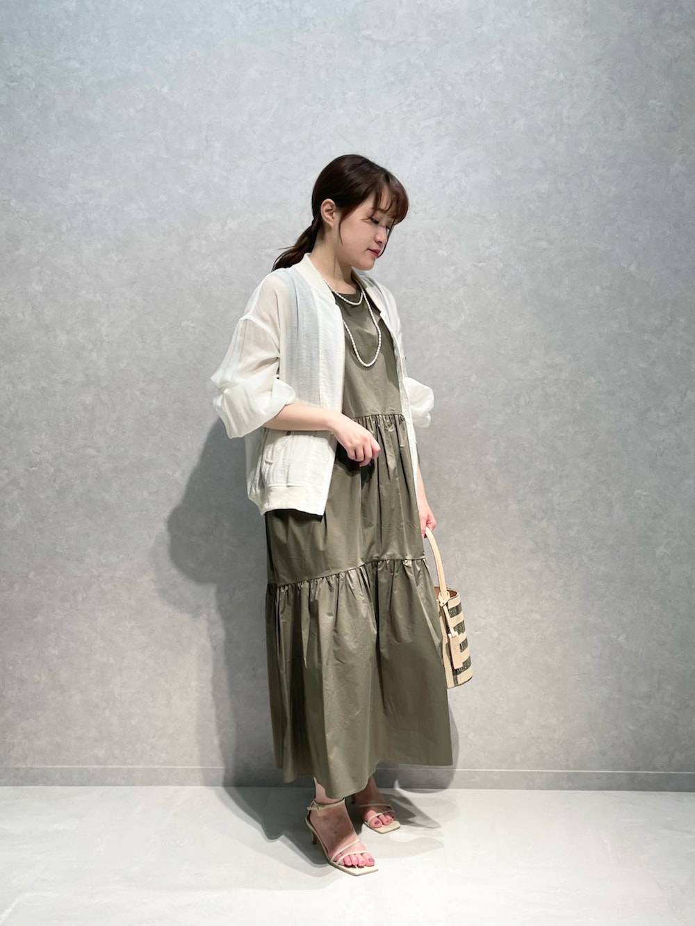 ホワイト系のミリタリージャケット、グリーン系のワンピースを着用したレディースの夏コーディネートの2枚目の写真