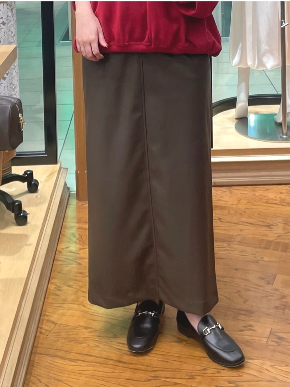 レッド系のスウェット、ブラウン系のスカート、ブラック系のローファーを着用したレディースの秋コーディネートの3枚目の写真