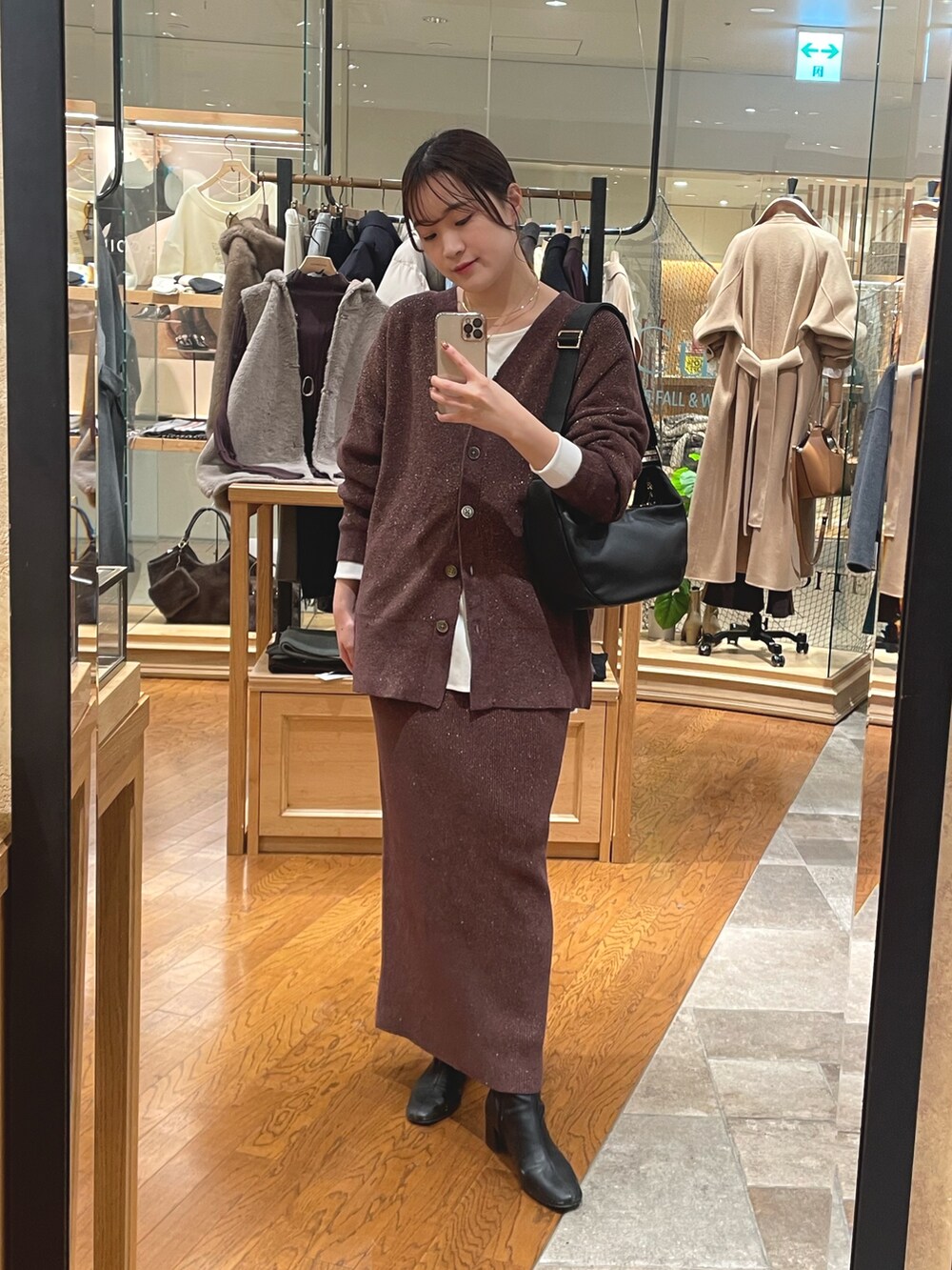 ブラウン系のスカート、ホワイト系のTシャツ/カットソー、ブラック系のショルダーバッグを着用したレディースの秋コーディネートの3枚目の写真