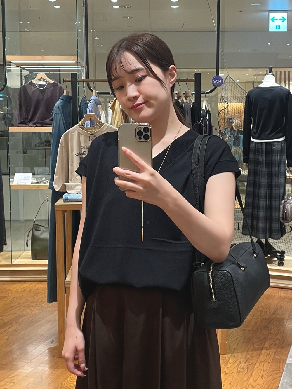 ブラック系のニット/セーター、ブラウン系のスカート、ブラック系のショルダーバッグを着用したレディースの秋コーディネートの2枚目の写真