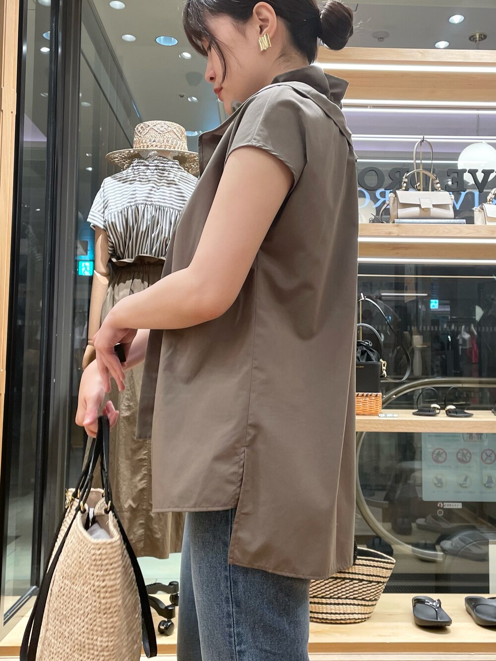 グリーン系のシャツ/ブラウス、ベージュ系のサンダル、ブルー系のデニムパンツを着用したレディースの春コーディネートの3枚目の写真