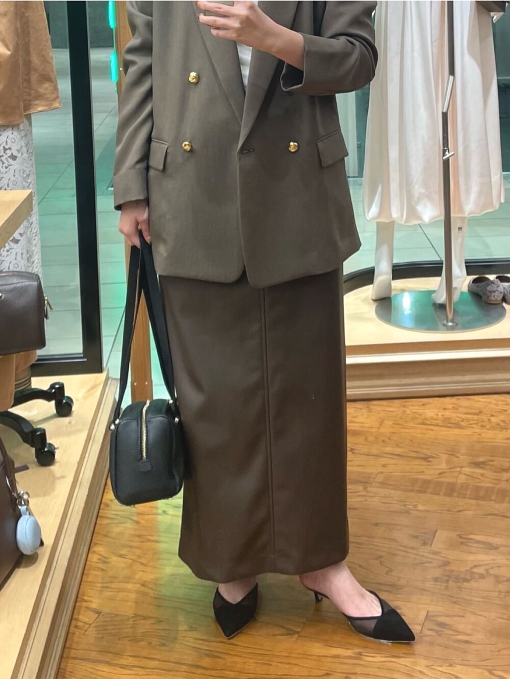 ブラウン系のテーラードジャケット、ブラウン系のスカート、ホワイト系のTシャツ/カットソーを着用したレディースの秋コーディネートの3枚目の写真