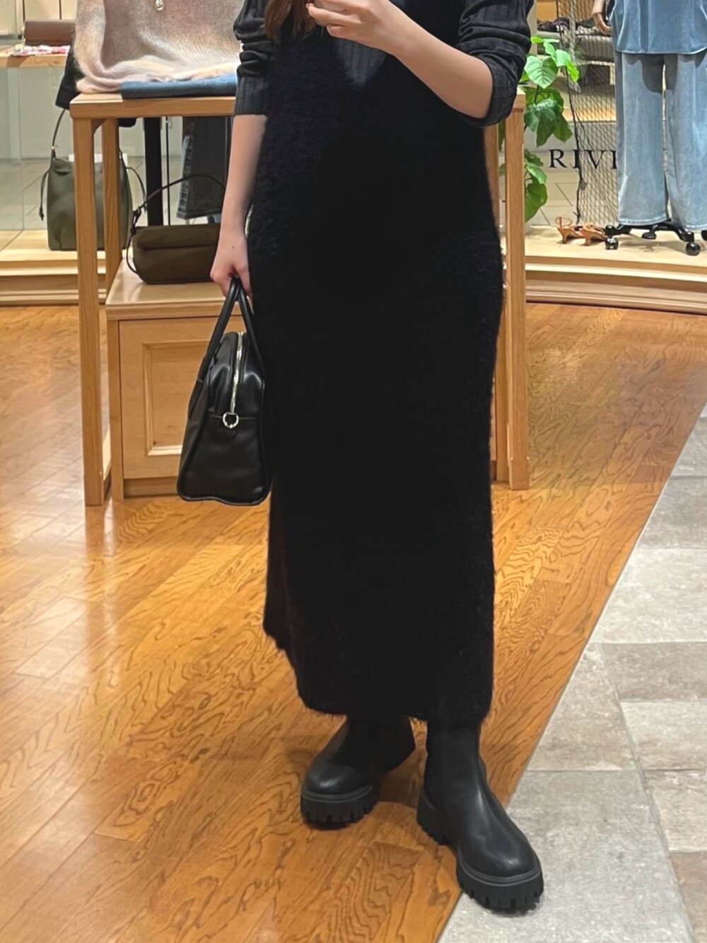 ブラック系のワンピース、ブラック系のブーツ、グレー系のニット/セーターを着用したレディースの秋コーディネートの3枚目の写真