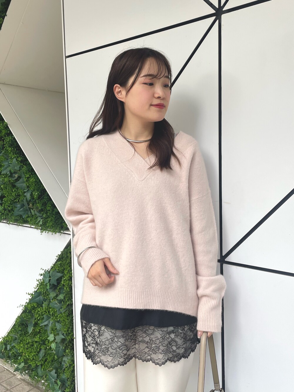 ベージュ系のハンドバッグ、ブラック系のパンプス、ピンク系のニット/セーターを着用したレディースの秋コーディネートの2枚目の写真