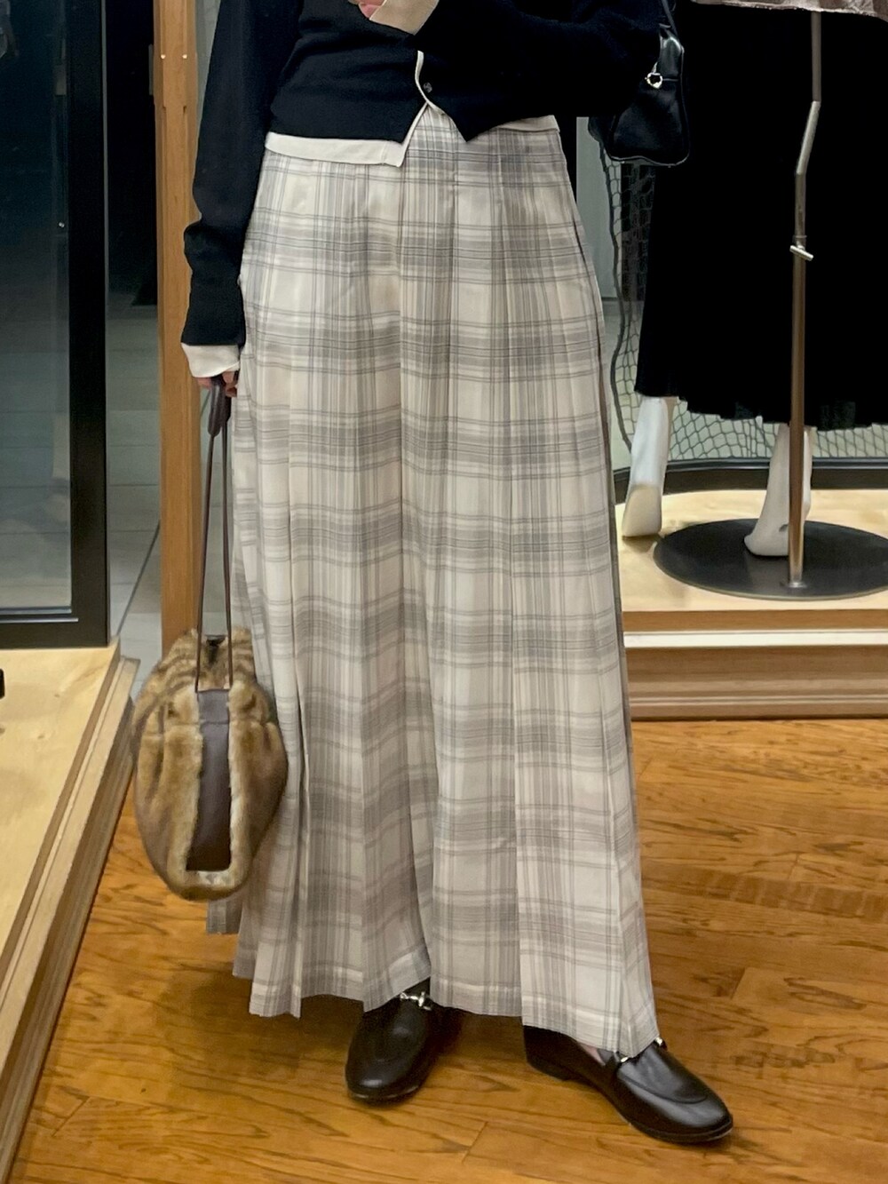 ブラック系のカーディガン/ボレロ、ホワイト系のスカート、イエロー系のハンドバッグを着用したレディースの夏コーディネートの3枚目の写真