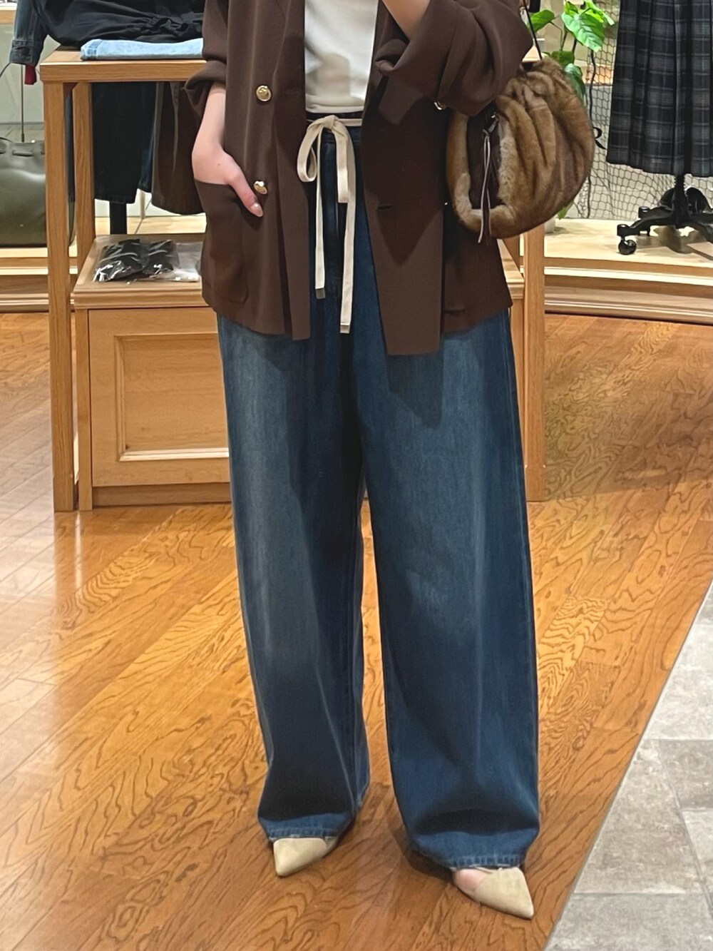 イエロー系のハンドバッグ、ブルー系のデニムパンツ、ベージュ系のパンプスを着用したレディースの夏コーディネートの3枚目の写真