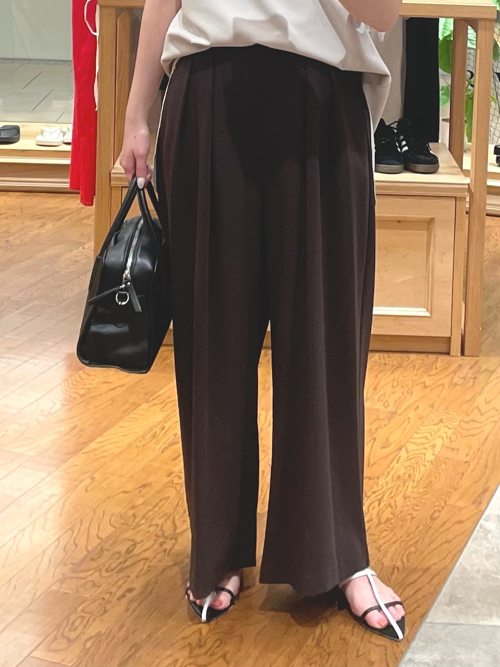 ブラウン系のスラックス、ベージュ系のTシャツ/カットソー、ブラック系のボストンバッグを着用したレディースの夏コーディネートの3枚目の写真