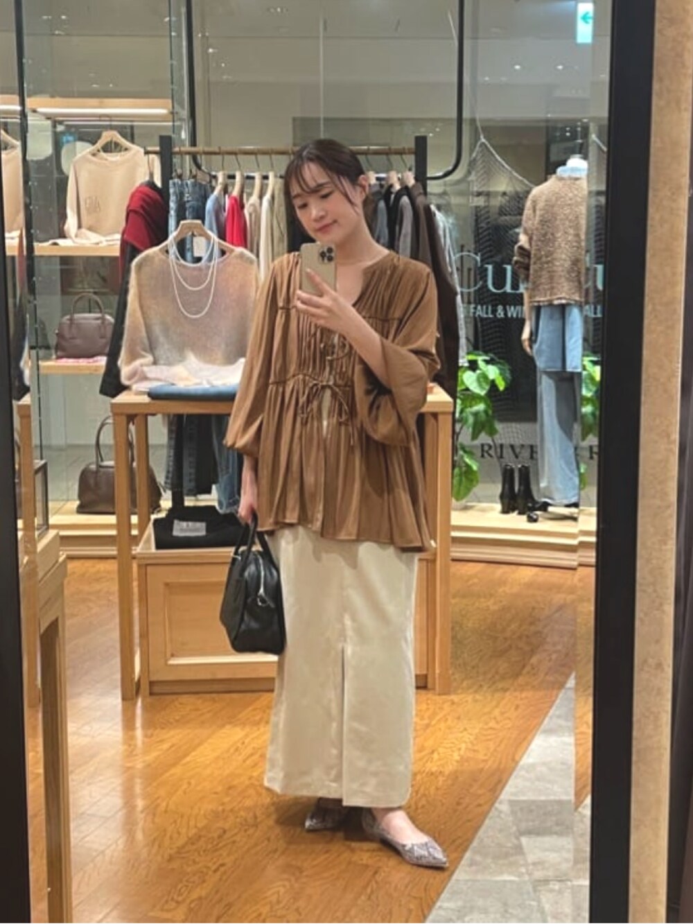 ベージュ系のスカート、ブラック系のボストンバッグ、グレー系のパンプスを着用したレディースの秋コーディネートの4枚目の写真