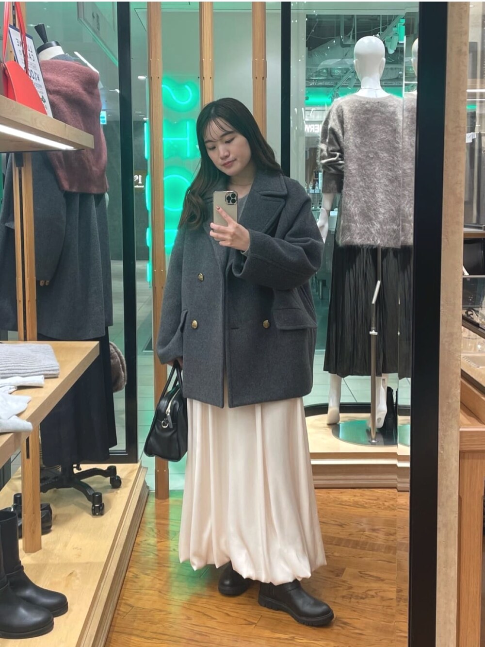 グレー系のピーコート、ホワイト系のスカート、ブラック系のボストンバッグを着用したレディースの秋コーディネートの3枚目の写真