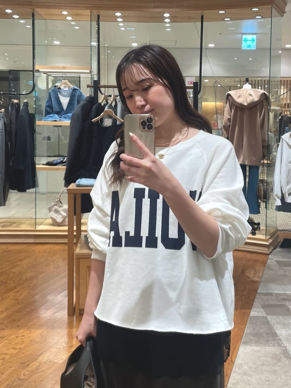 ホワイト系のスウェット、ブラウン系のキャミソール、ブラウン系のスカートを着用したレディースの冬コーディネートの2枚目の写真