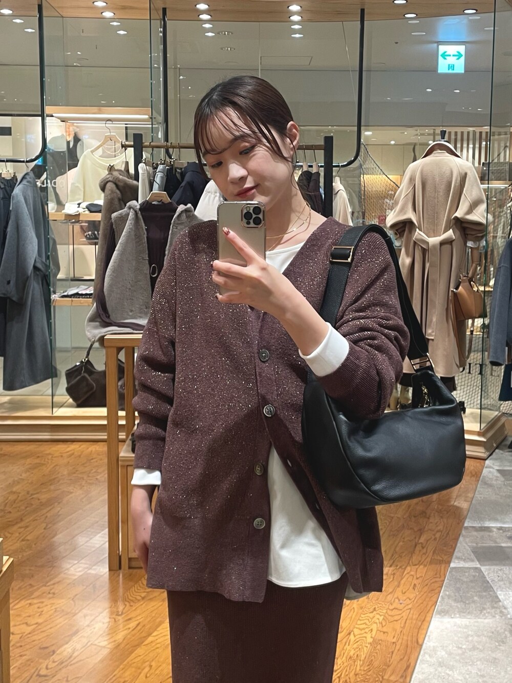 ブラウン系のスカート、ホワイト系のTシャツ/カットソー、ブラック系のショルダーバッグを着用したレディースの秋コーディネートの2枚目の写真