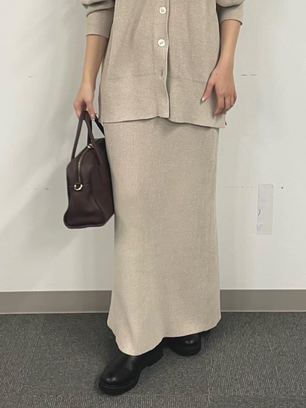 ホワイト系のニット/セーター、ブラック系のブーツ、ホワイト系のスカートを着用したレディースの秋コーディネートの4枚目の写真