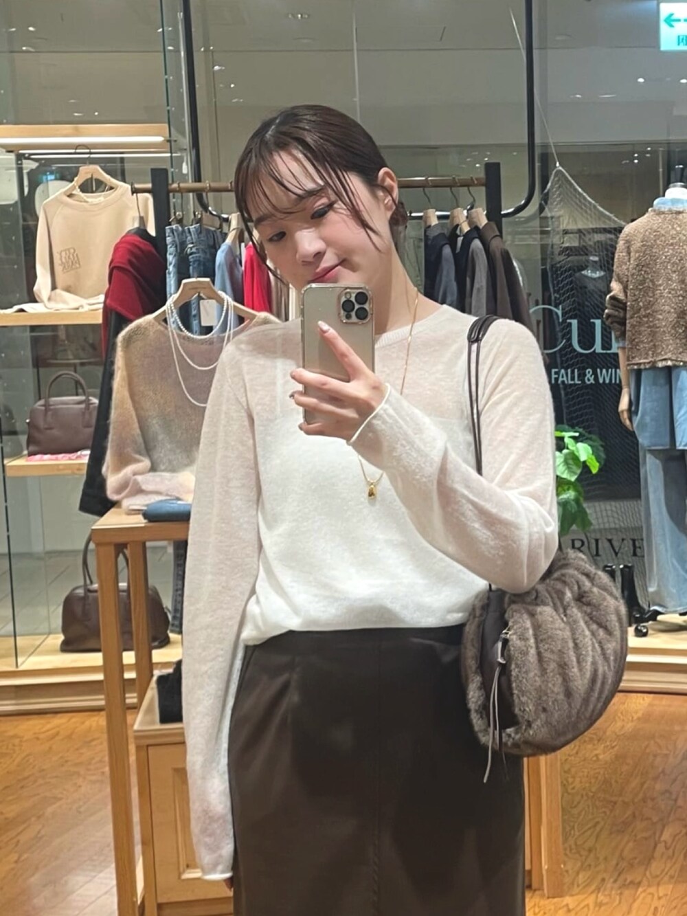 ブラウン系のスカート、ブラウン系のハンドバッグ、ブラック系のブーツを着用したレディースの秋コーディネートの2枚目の写真