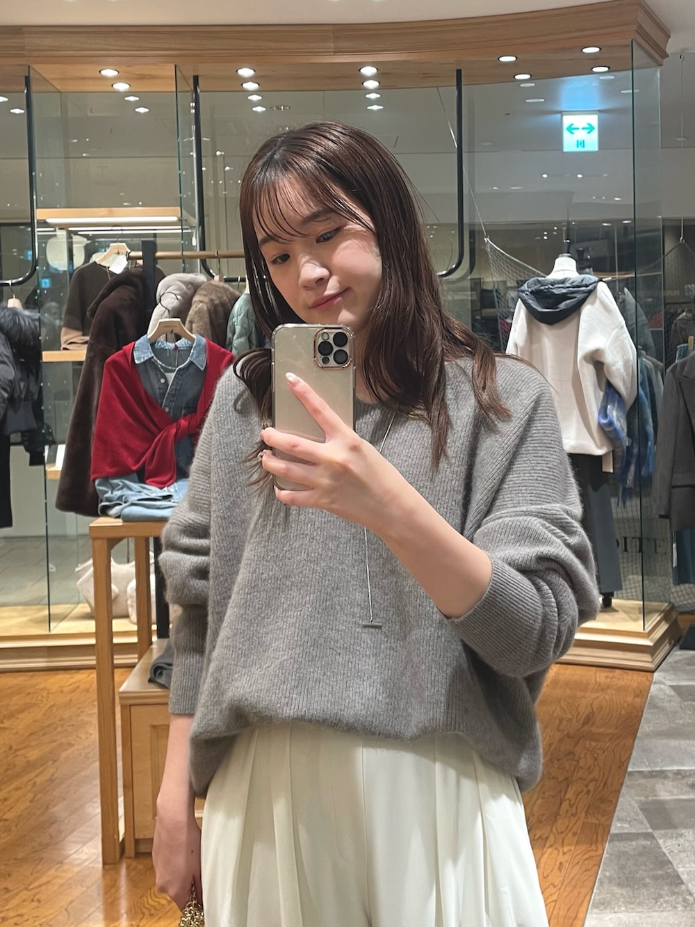 グレー系のニット/セーター、ホワイト系のスラックス、ブラウン系のブーツを着用したレディースの秋コーディネートの2枚目の写真