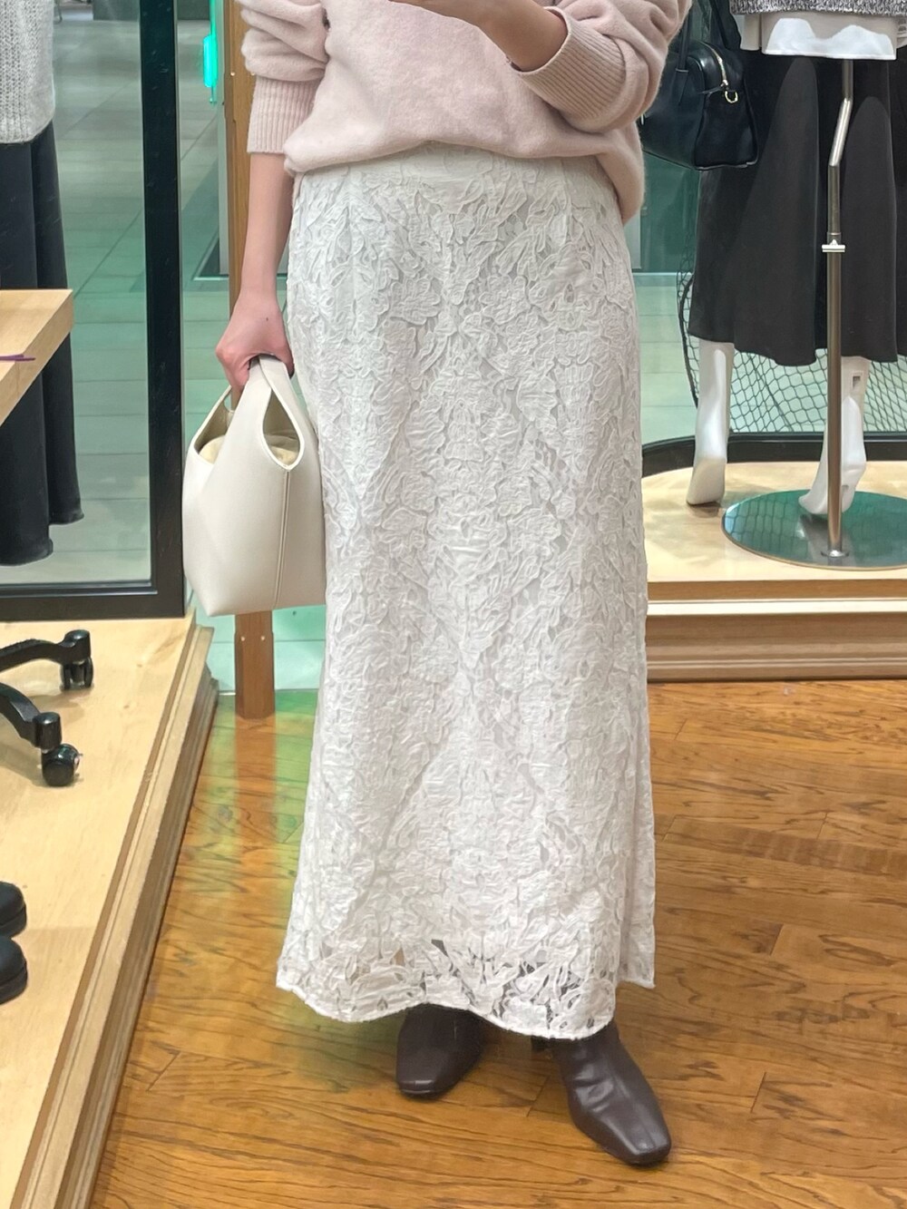 ピンク系のニット/セーター、ホワイト系のスカート、ホワイト系のハンドバッグを着用したレディースの秋コーディネートの3枚目の写真