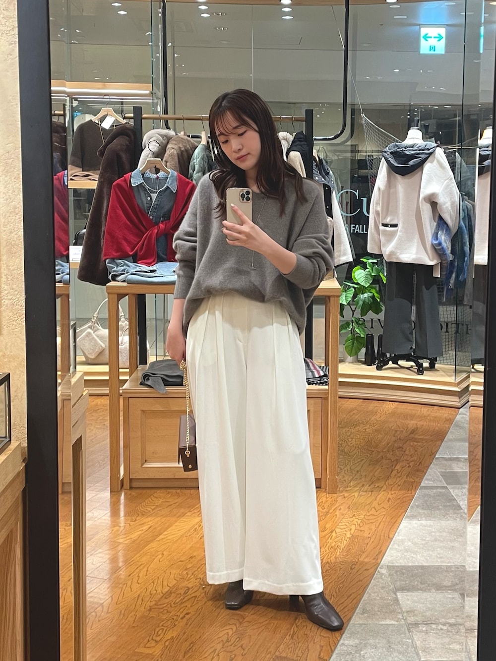 グレー系のニット/セーター、ホワイト系のスラックス、ブラウン系のブーツを着用したレディースの秋コーディネートの3枚目の写真