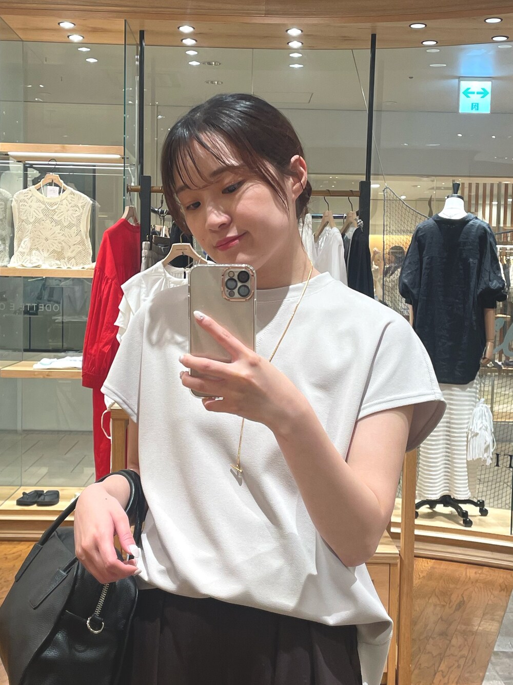 ブラウン系のスラックス、ベージュ系のTシャツ/カットソー、ブラック系のボストンバッグを着用したレディースの夏コーディネートの2枚目の写真