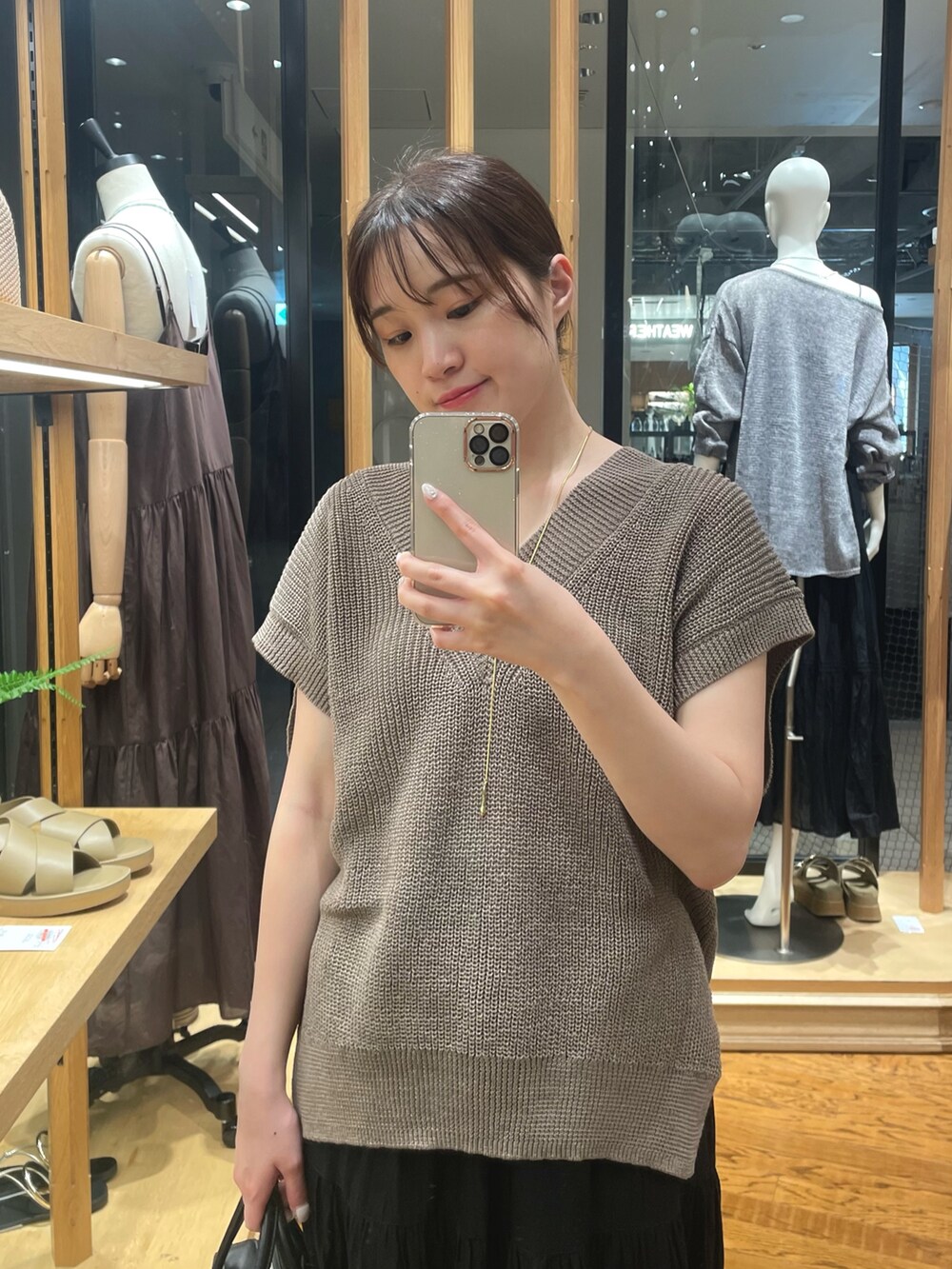 ブラウン系のニット/セーター、ブラック系のボストンバッグ、ゴールド系のネックレスを着用したレディースの夏コーディネートの2枚目の写真