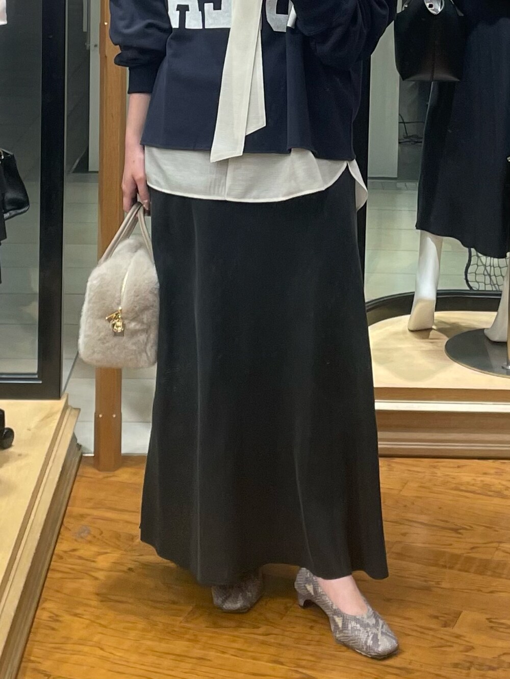 ブラック系のスカート、ベージュ系のボストンバッグ、ブルー系のスウェットを着用したレディースの冬コーディネートの3枚目の写真