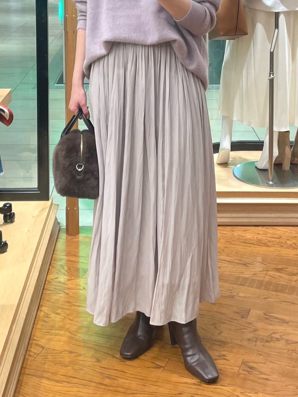 パープル系のニット/セーター、ブラウン系のボストンバッグ、ブラウン系のブーツを着用したレディースの冬コーディネートの3枚目の写真