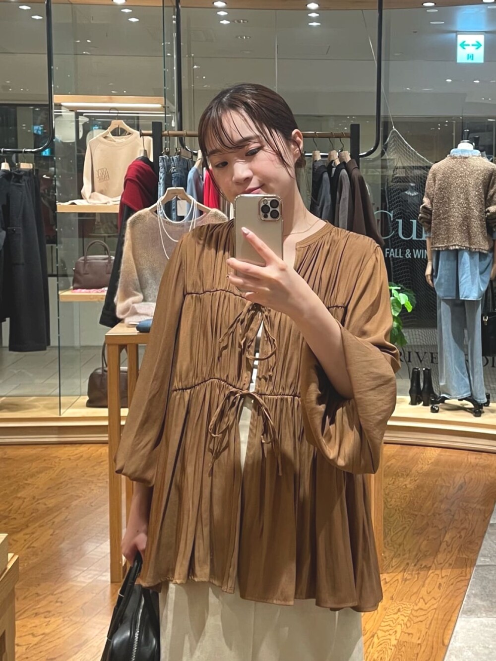 ベージュ系のスカート、ブラック系のボストンバッグ、グレー系のパンプスを着用したレディースの秋コーディネートの2枚目の写真