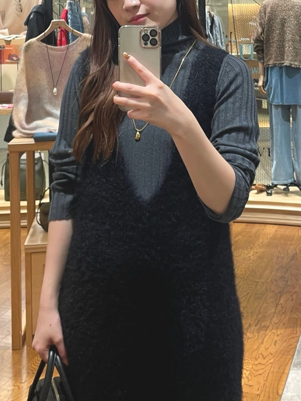 ブラック系のワンピース、ブラック系のブーツ、グレー系のニット/セーターを着用したレディースの秋コーディネートの2枚目の写真