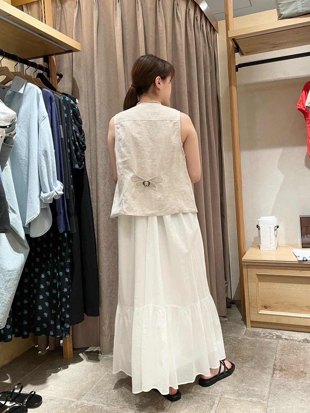 ベージュ系のその他アウター、ホワイト系のワンピース、ブラック系のサンダルを着用したレディースの夏コーディネートの3枚目の写真