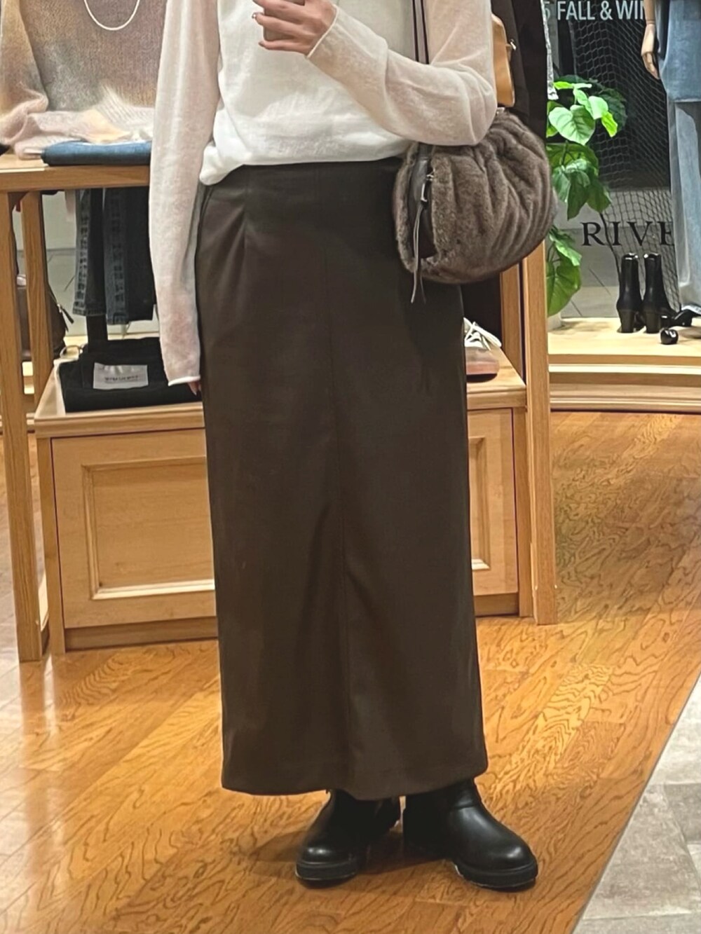 ブラウン系のスカート、ブラウン系のハンドバッグ、ブラック系のブーツを着用したレディースの秋コーディネートの3枚目の写真