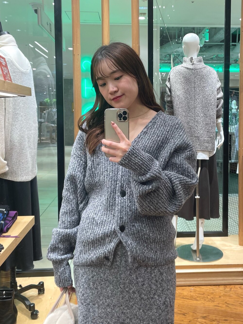 グレー系のカーディガン/ボレロ、グレー系のスカート、ベージュ系のボストンバッグを着用したレディースの秋コーディネートの2枚目の写真