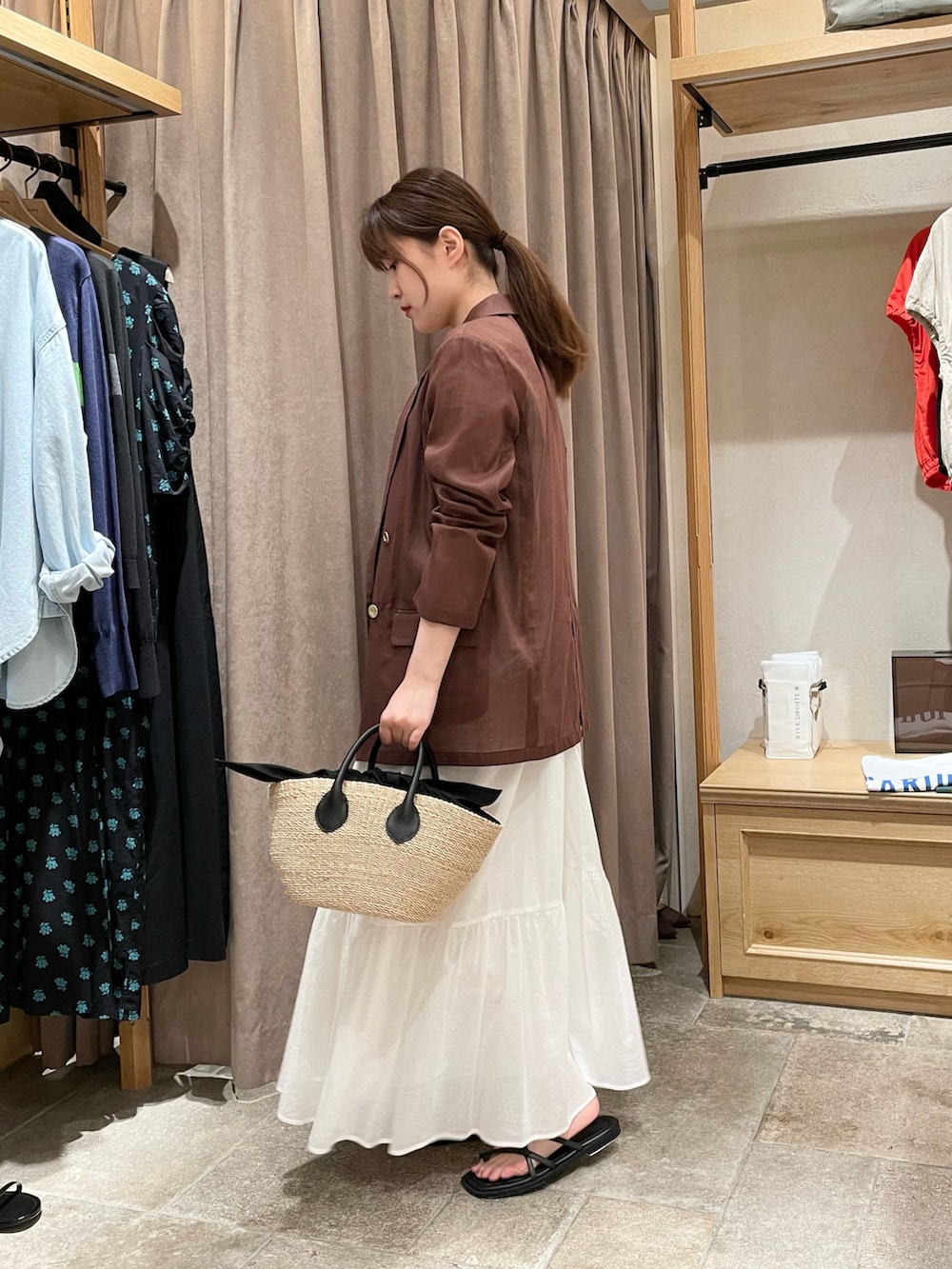 ブラウン系のテーラードジャケット、ホワイト系のワンピース、ブラック系のショルダーバッグを着用したレディースの夏コーディネートの2枚目の写真
