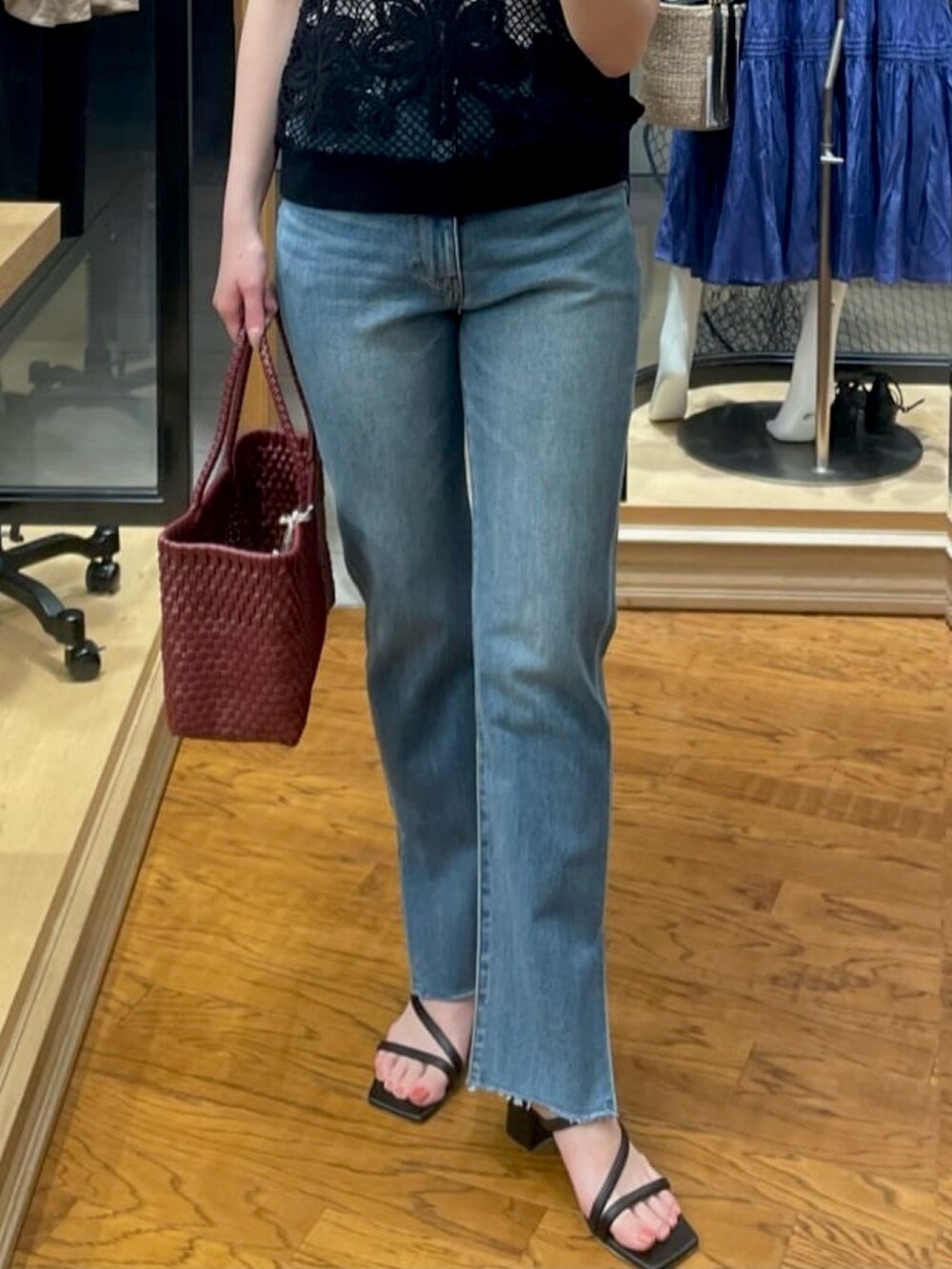 ブラック系のニット/セーター、ブルー系のデニムパンツ、ブラック系のサンダルを着用したレディースの夏コーディネートの3枚目の写真