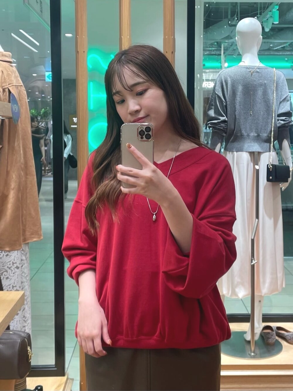 レッド系のスウェット、ブラウン系のスカート、ブラック系のローファーを着用したレディースの秋コーディネートの2枚目の写真