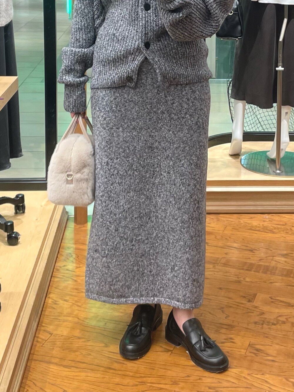 グレー系のカーディガン/ボレロ、グレー系のスカート、ベージュ系のボストンバッグを着用したレディースの秋コーディネートの3枚目の写真