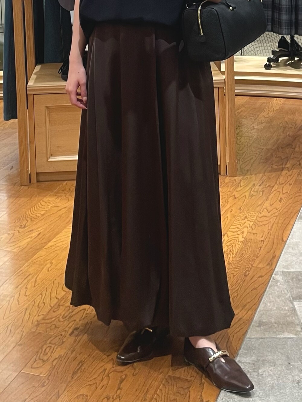 ブラック系のニット/セーター、ブラウン系のスカート、ブラック系のショルダーバッグを着用したレディースの秋コーディネートの3枚目の写真