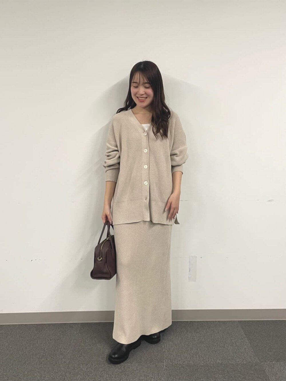 ホワイト系のニット/セーター、ブラック系のブーツ、ホワイト系のスカートを着用したレディースの秋コーディネートの5枚目の写真