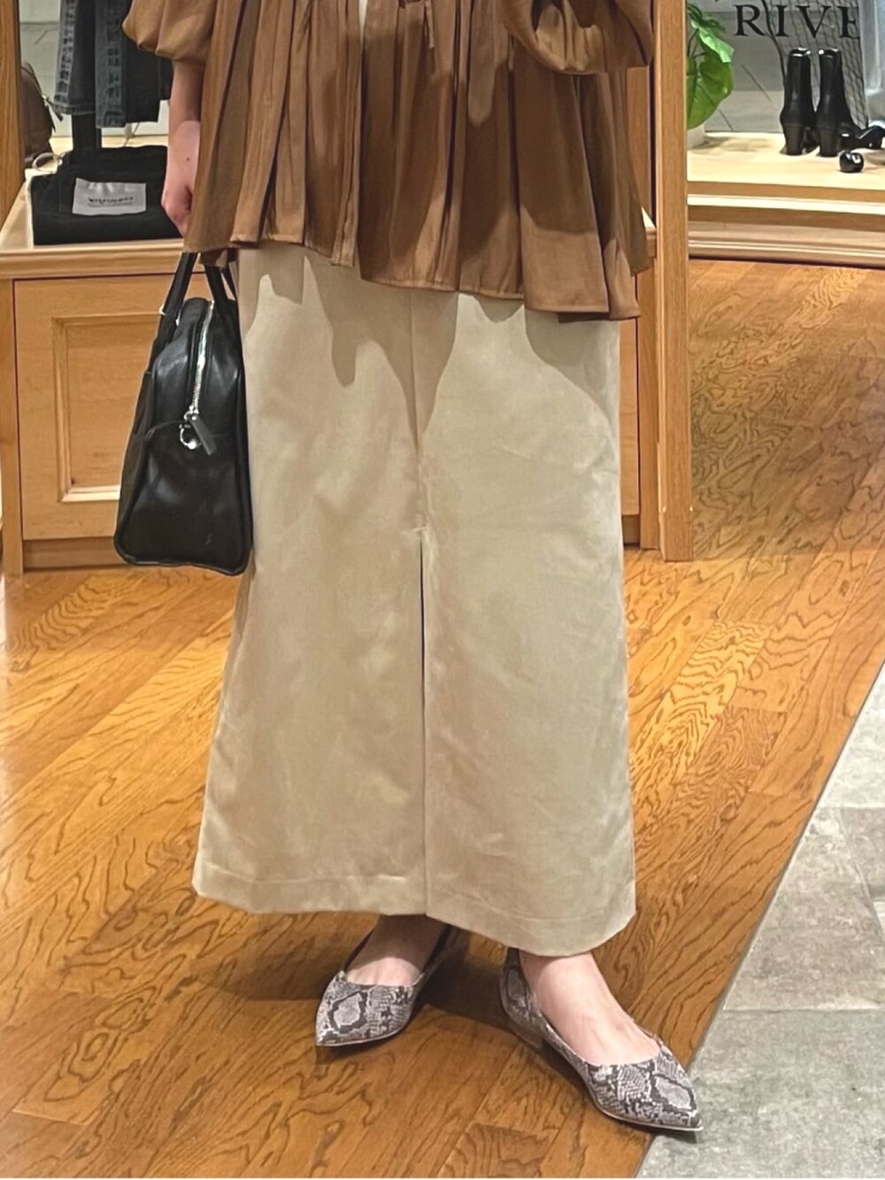 ベージュ系のスカート、ブラック系のボストンバッグ、グレー系のパンプスを着用したレディースの秋コーディネートの3枚目の写真