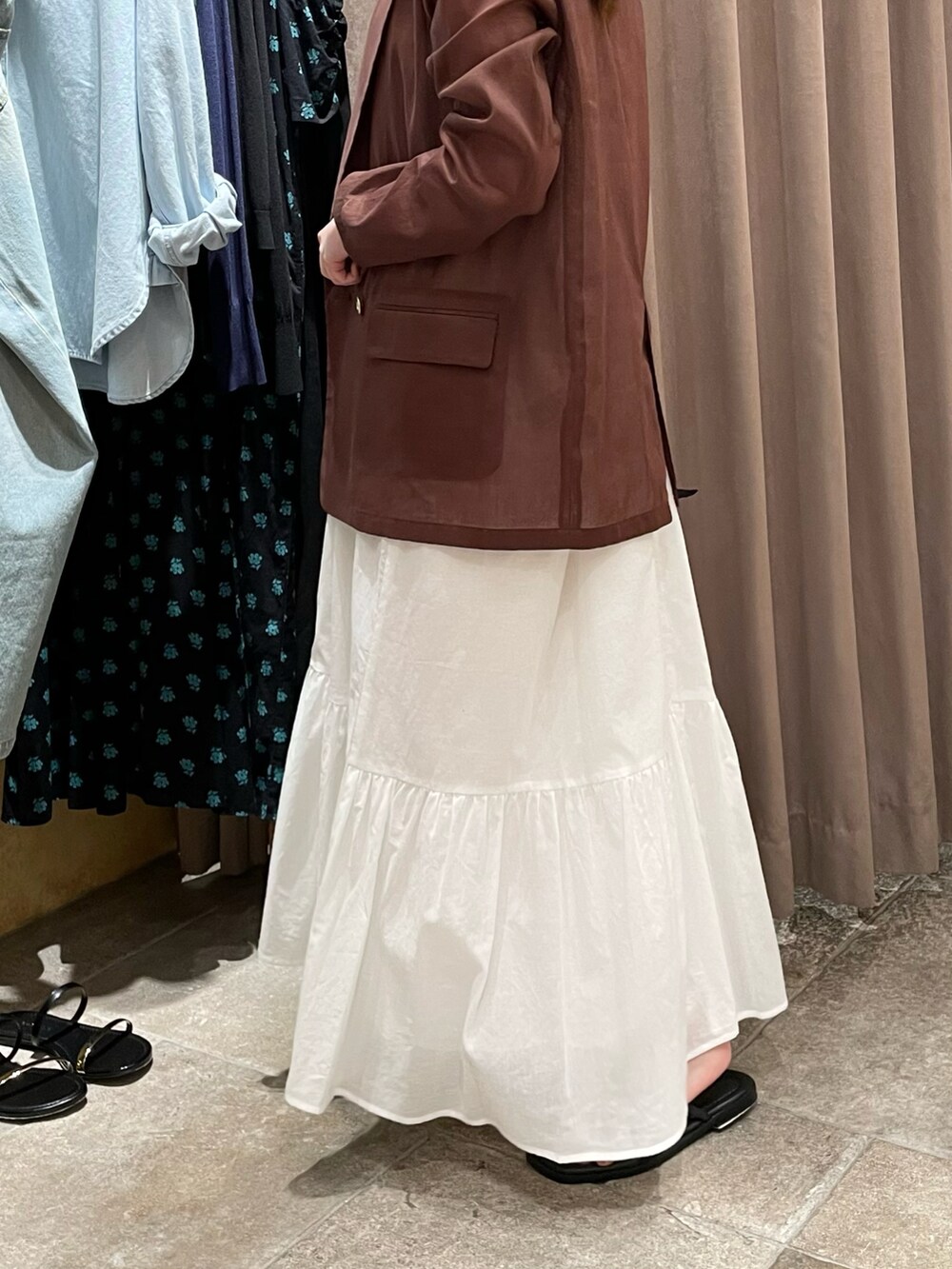 ブラウン系のテーラードジャケット、ホワイト系のワンピース、ブラック系のショルダーバッグを着用したレディースの夏コーディネートの4枚目の写真