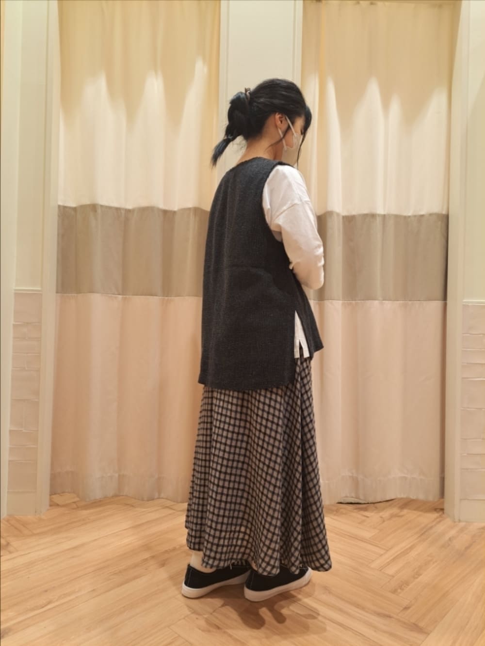 グレー系のベスト、ホワイト系のTシャツ/カットソー、グレー系のスカートを着用したレディースの秋コーディネートの2枚目の写真