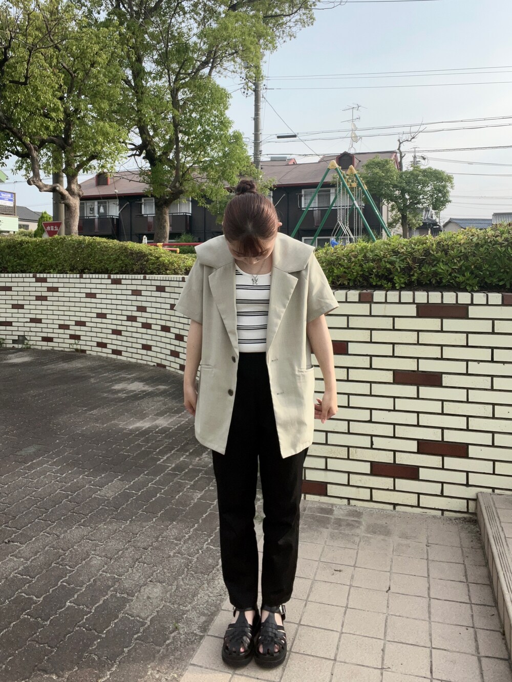 グリーン系のテーラードジャケット、ホワイト系のタンクトップ、ブラック系のパンツを着用したレディースの夏コーディネートの2枚目の写真