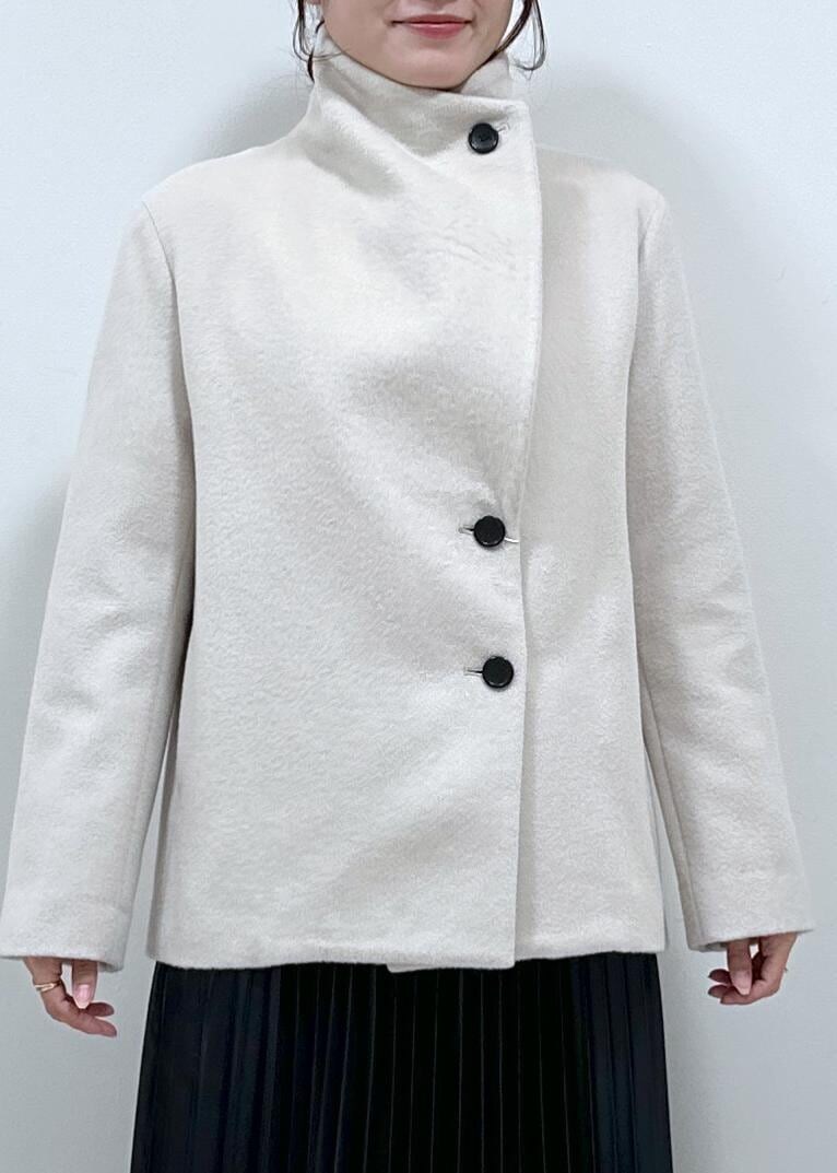 ブラック系のブーツ、ブラウン系のハンドバッグ、ホワイト系のステンカラーコートを着用したレディースの秋コーディネートの2枚目の写真