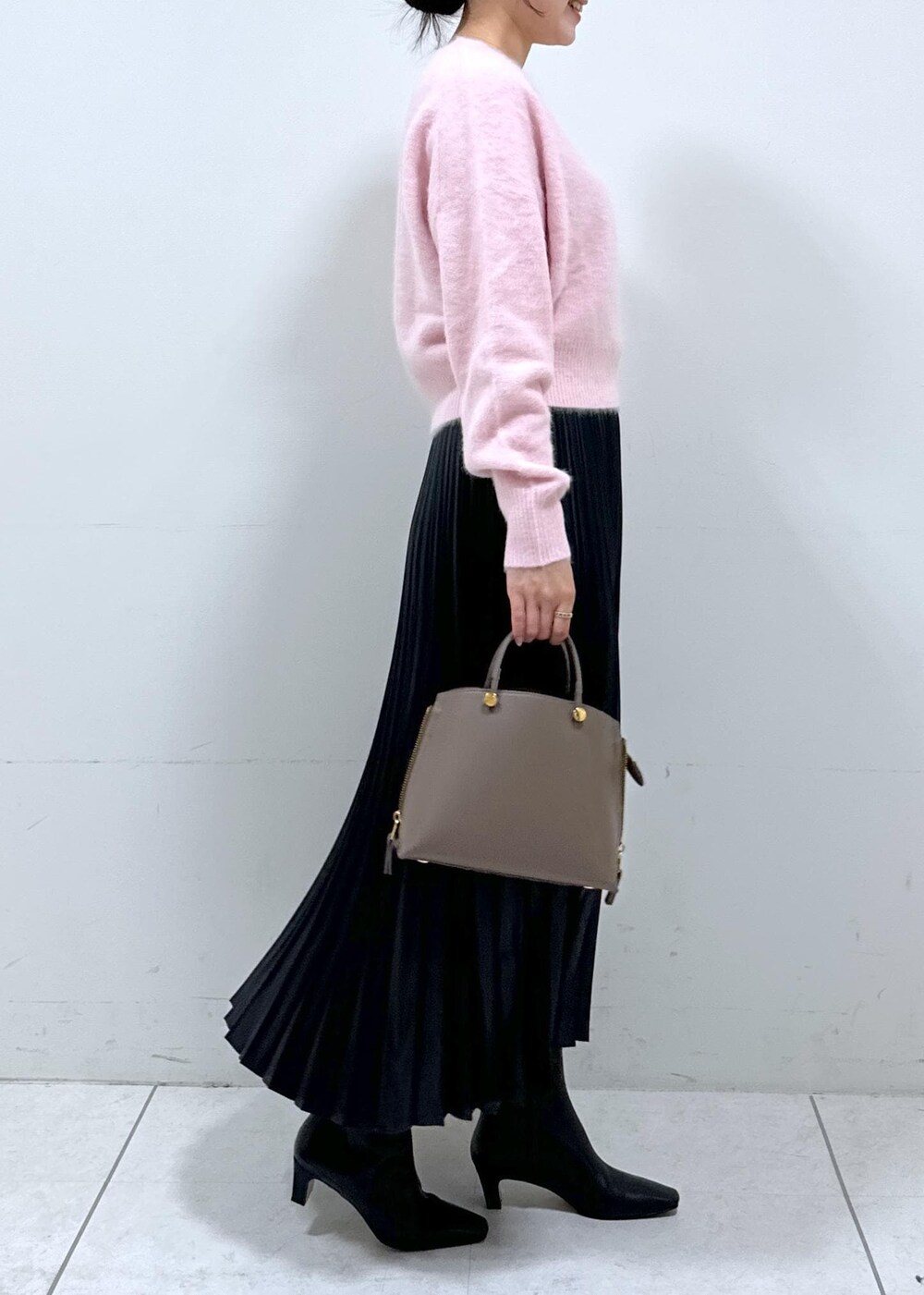 ブラック系のブーツ、ブラウン系のハンドバッグ、ホワイト系のステンカラーコートを着用したレディースの秋コーディネートの8枚目の写真