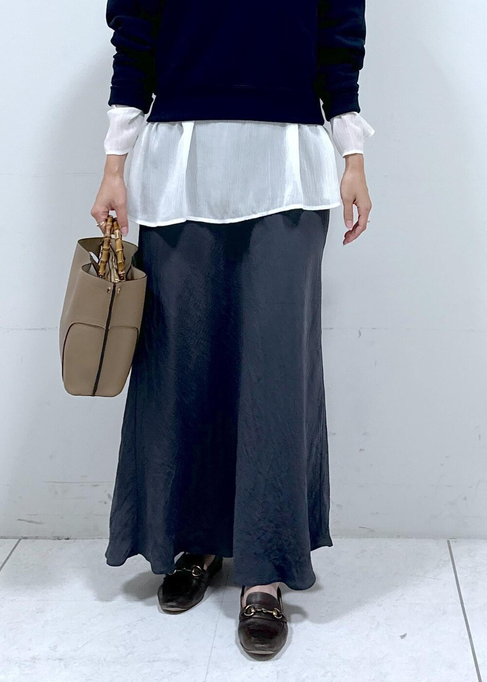 グレー系のスカート、ホワイト系のシャツ/ブラウス、ブルー系のスウェットを着用したレディースの秋コーディネートの4枚目の写真