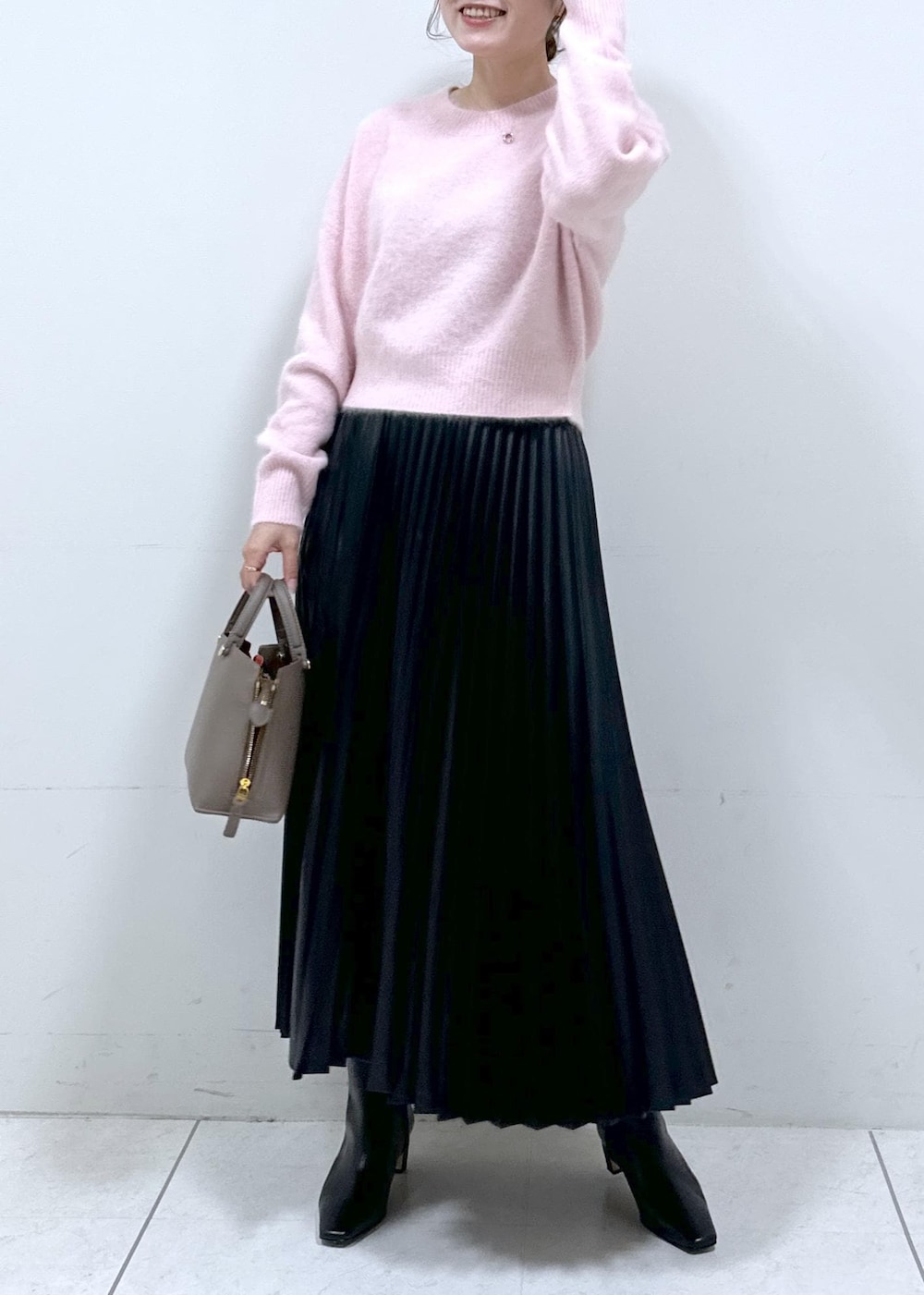 ブラック系のブーツ、ブラウン系のハンドバッグ、ホワイト系のステンカラーコートを着用したレディースの秋コーディネートの5枚目の写真