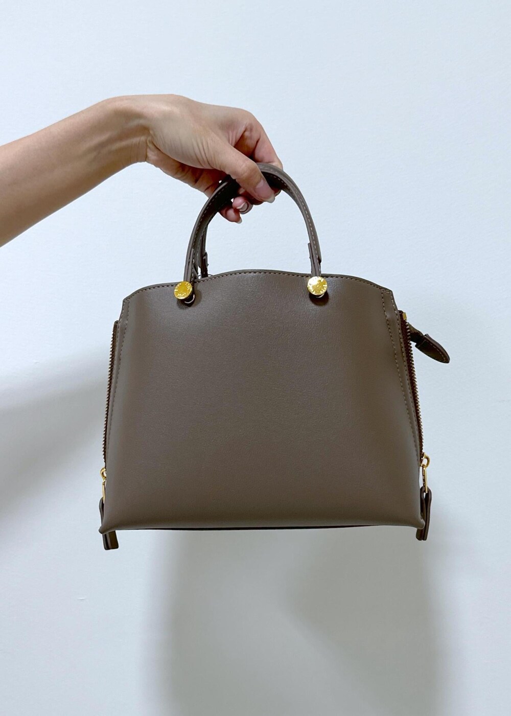 ブラック系のブーツ、ブラウン系のハンドバッグ、ホワイト系のステンカラーコートを着用したレディースの秋コーディネートの10枚目の写真