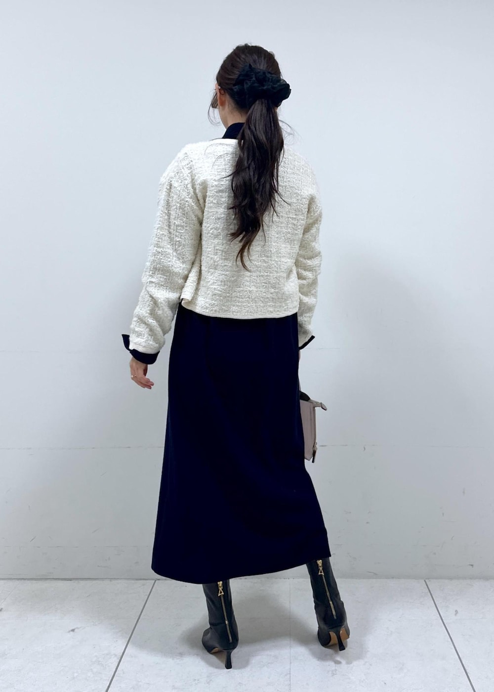 グレー系のハンドバッグ、ブルー系のワンピース、ホワイト系のカーディガン/ボレロを着用したレディースの冬コーディネートの4枚目の写真