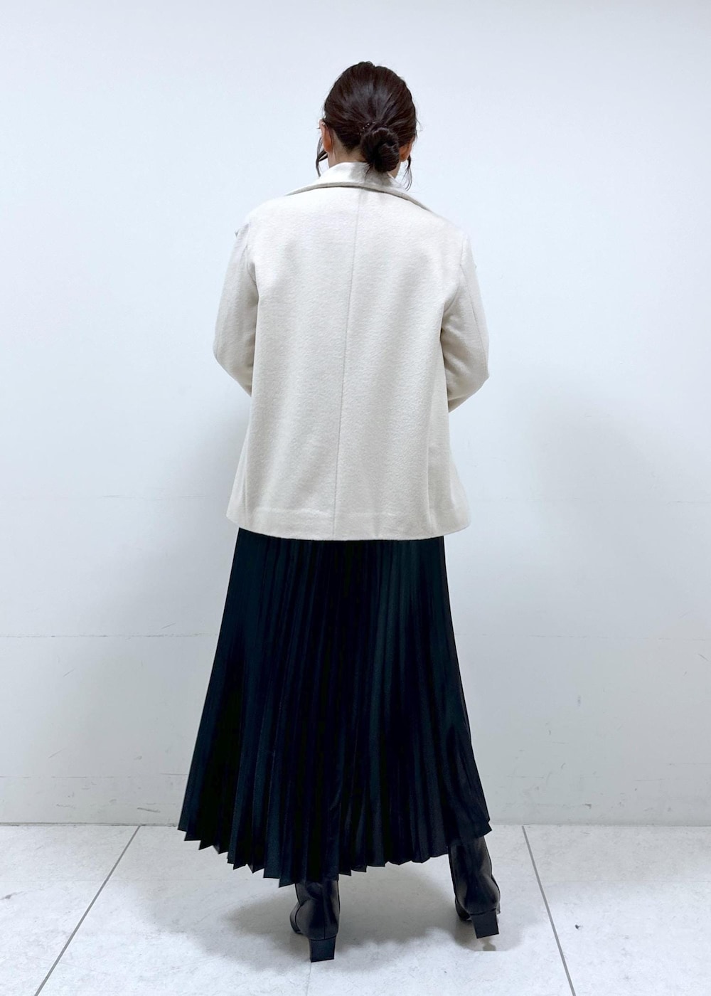 ブラック系のブーツ、ブラウン系のハンドバッグ、ホワイト系のステンカラーコートを着用したレディースの秋コーディネートの4枚目の写真