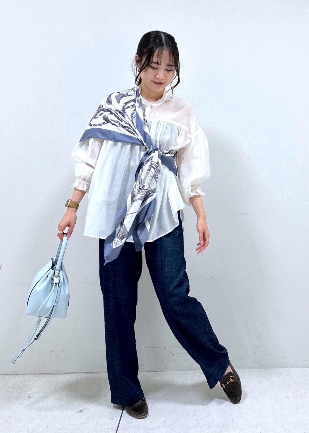 ブラウン系のローファー、ブルー系のハンドバッグ、ブルー系のデニムパンツを着用したレディースの冬コーディネートの2枚目の写真